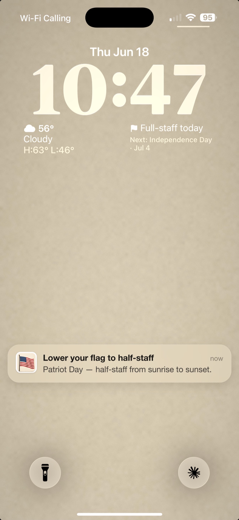 An iPhone Lock Screen with a FlagPole notification: Lower your flag to half-staff for Patriot Day, half-staff from sunrise to sunset.